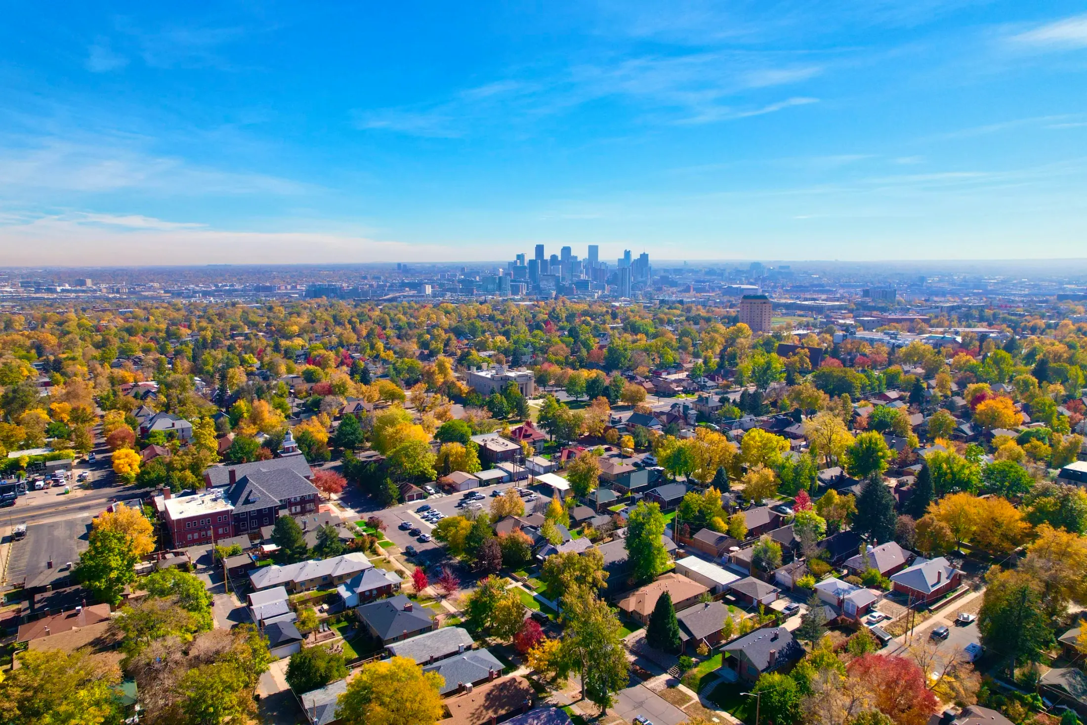 Drone photo of Denver residential neighborhoods in fall with the downtown skyline in the distance
