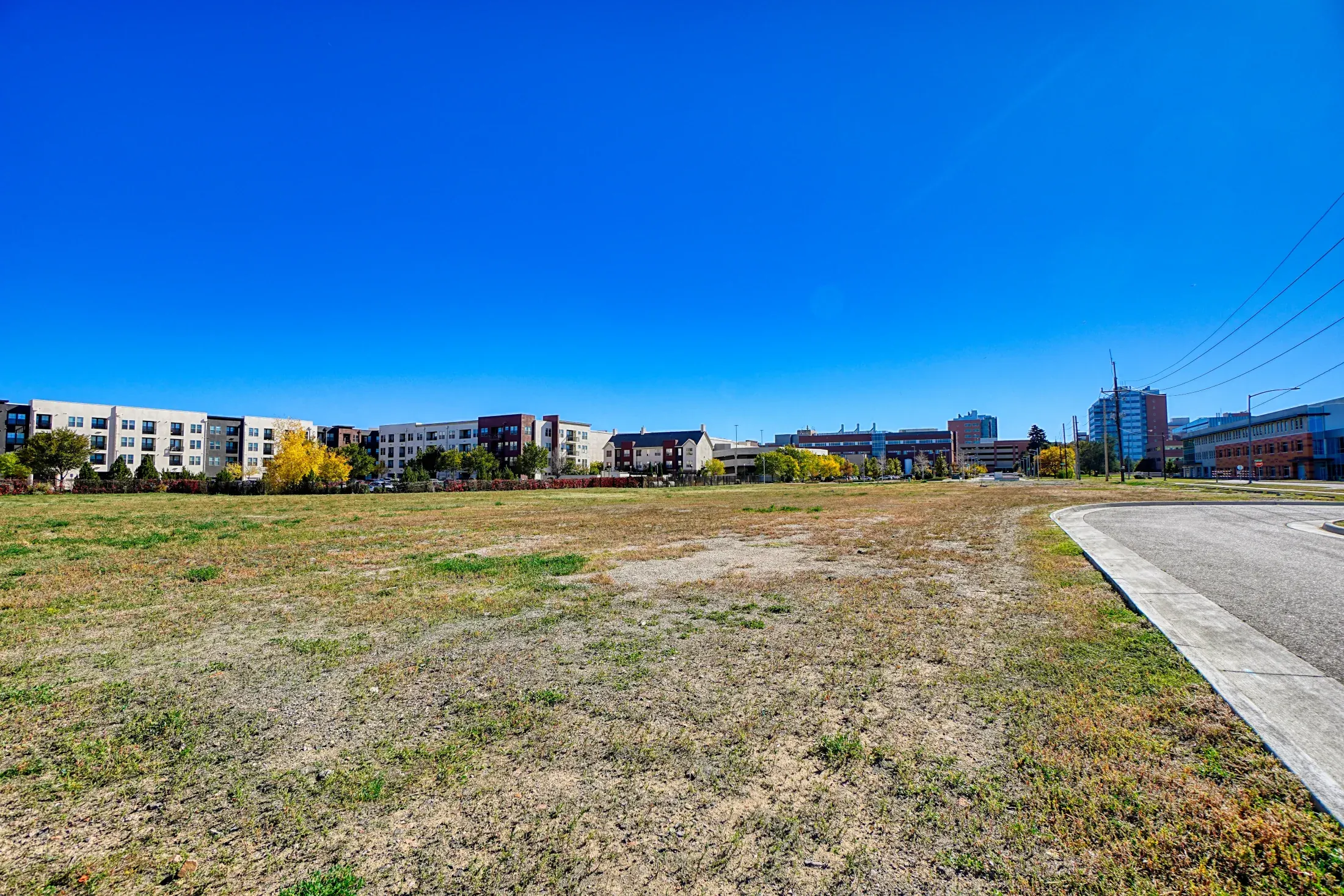 Ground-level vacant land photo showing access, vegetation, and terrain context